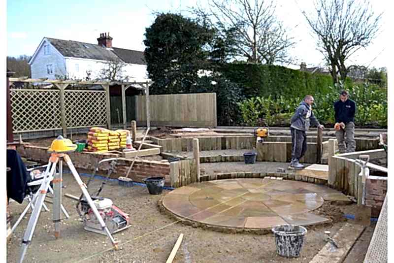 Building the central paving feature with trellis and fencing in the background